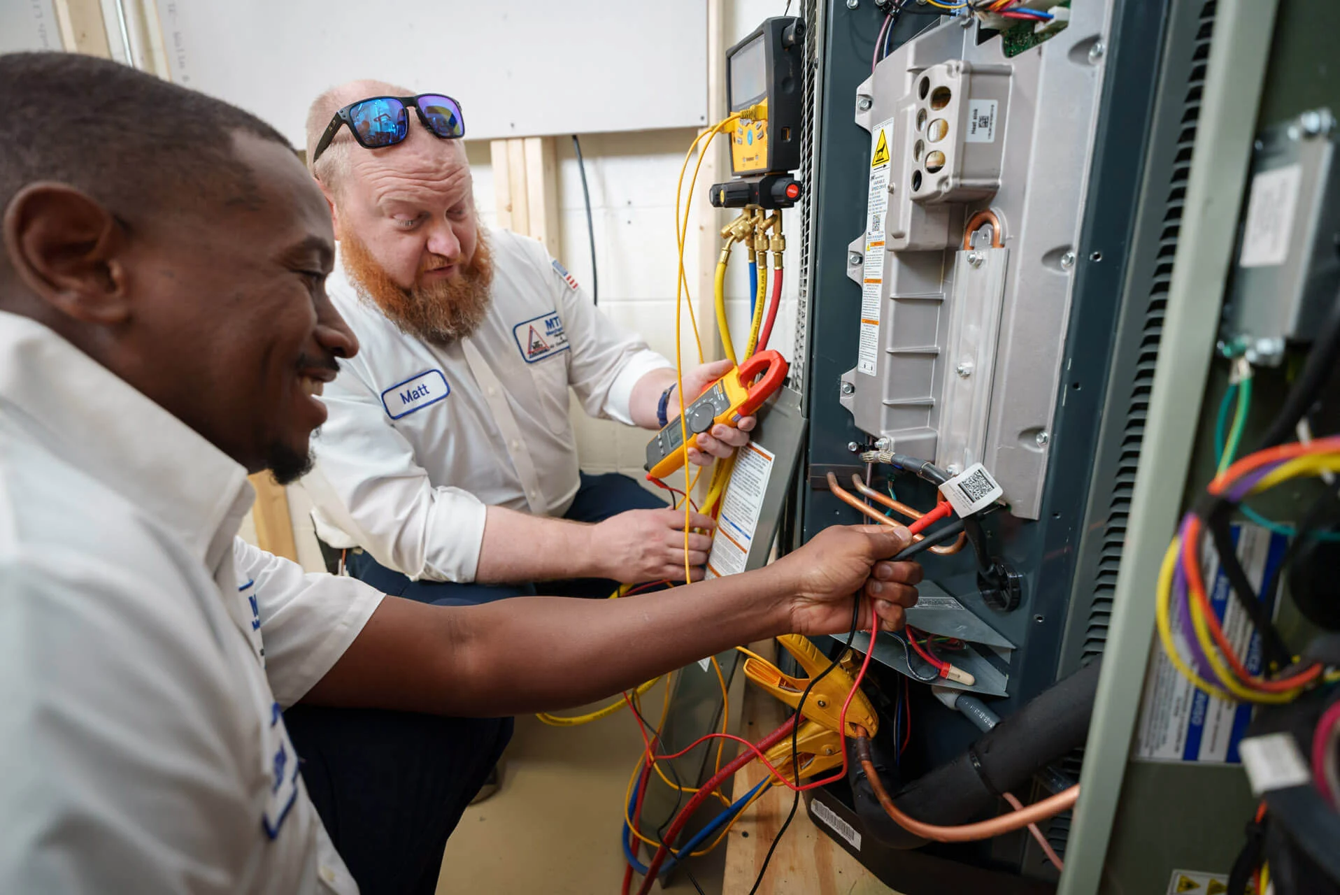 Two-MTB-Mechanical-Heating-Air-Conditioning-technicians-performing-diagnostics-on-a-control-panel - MTB Mechanical Two-MTB-Mechanical-Heating-Air-Conditioning-technicians-performing-diagnostics-on-a-control-panel